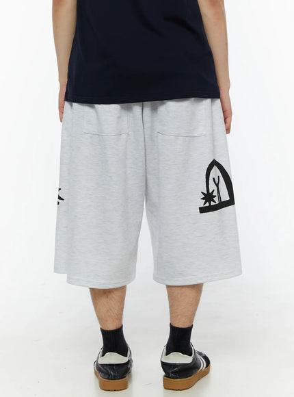 Men's Shooting Star Printed Shorts (Light Gray) IL509 Light gray back view on model showing arch figure and star graphic print on both legs, patch pockets, wide fit