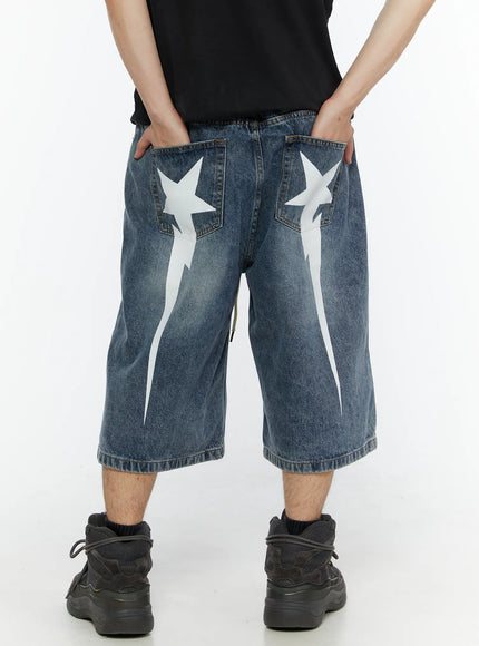 Men's Star Bolt Graphic Print Jorts (Blue) IL507 Blue back view on model hands in pockets showing white star bolt graphic print and wide-leg washed denim silhouette
