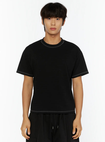 Men's Stitched Cropped T-Shirt IL513 Black front view on male model standing straight, contrast overlock stitching at neckline, sleeve cuffs, and hem