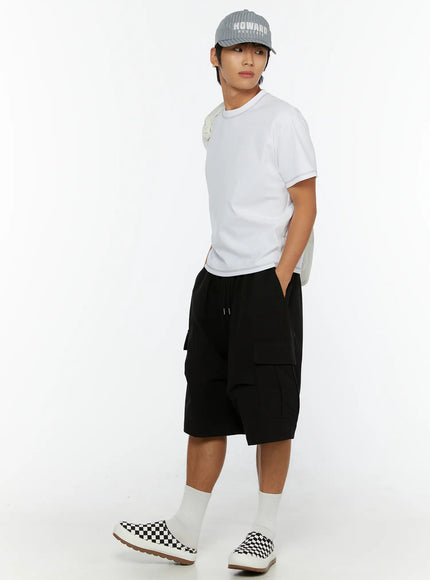 Men's Stitched Cropped T-Shirt IL513 White side lifestyle full-body shot on male model with cap, shoulder bag, black cargo shorts, checkered sneakers