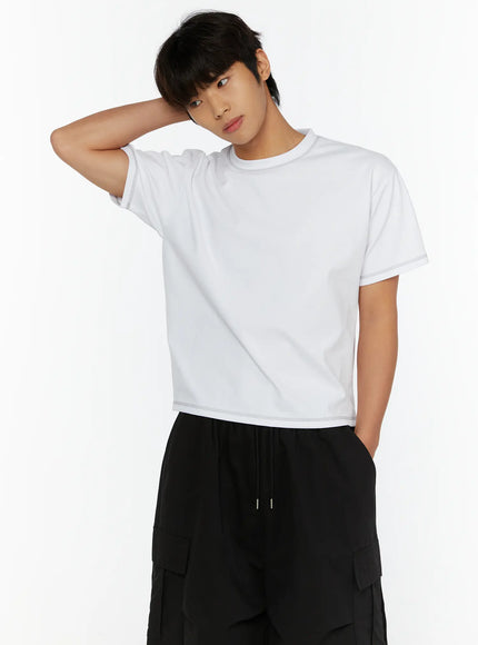 Men's Stitched Cropped T-Shirt IL513 White upper-body front close-up on male model with hand behind head, contrast stitching at crewneck and cropped hem
