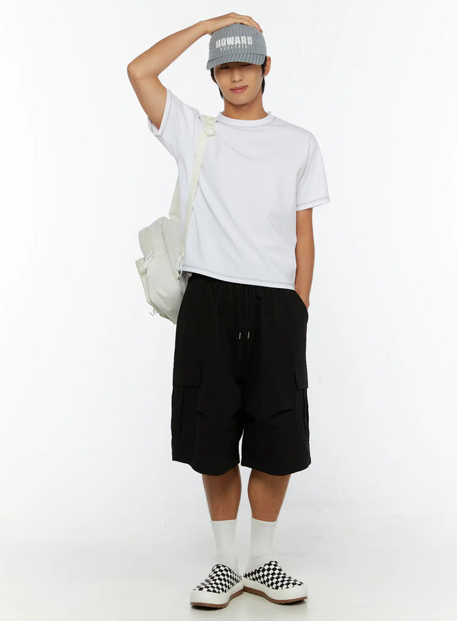 LEWKIN Men's Stitched Cropped T-Shirt IL513 White M/L full-body lifestyle shot on model with cap, crossbody bag, black cargo shorts, checkered sneakers