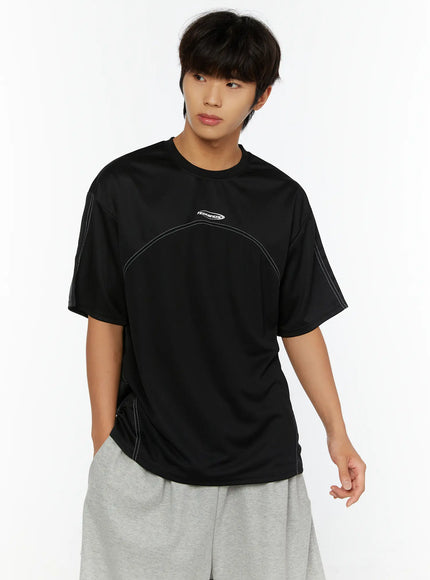 Men's Stitched T-Shirt IL513 Black front shot on male model looking sideways showing TEAM.BEGIN logo and white contrast stitch curved seam