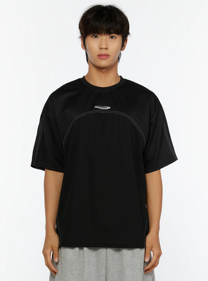 Men's Stitched T-Shirt IL513 Black front shot on male model standing neutral showing TEAM.BEGIN logo and white contrast stitch curved seam