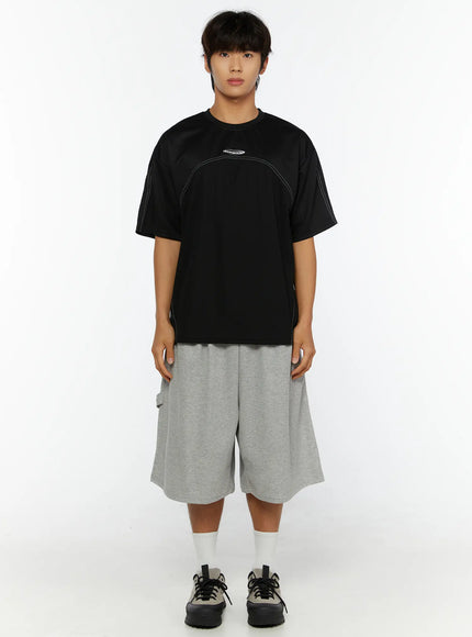 Men's Stitched T-Shirt IL513 Black full-body front shot on male model standing straight styled with gray cargo shorts and sneakers