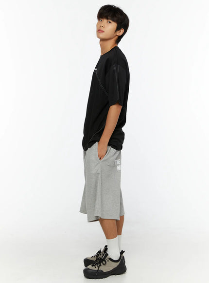 Men's Stitched T-Shirt IL513 Black full-body side shot on male model with hand in pocket showing oversized silhouette and hem length