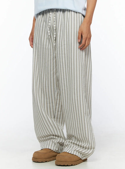 Men's Striped Wide-Leg Pants IL515 Light beige side-angle close-up on model showing wide-leg silhouette and vertical stripe seersucker fabric, styled with blue tee