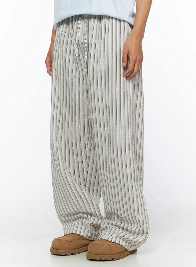Men's Striped Wide-Leg Pants IL515 Light beige side-angle close-up on model showing wide-leg silhouette and vertical stripe seersucker fabric, styled with blue tee