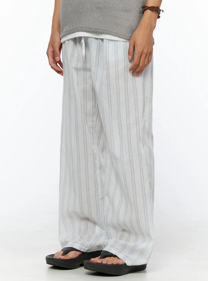 Men's Striped Wide-Leg Pants IL520 Light blue side-angle view on model holding striped tote bag, showing relaxed wide-leg fit and full length