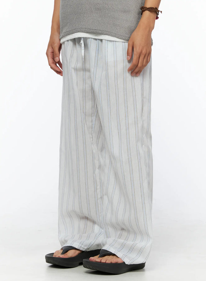 Men's Striped Wide-Leg Pants IL520 Light blue side-angle view on model holding striped tote bag, showing relaxed wide-leg fit and full length