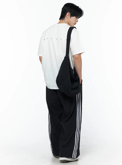 Men's Striped Wide Leg Track Pants IL502 Black back shot on male model wearing white tee and crossbody bag showing white triple side stripes and wide leg
