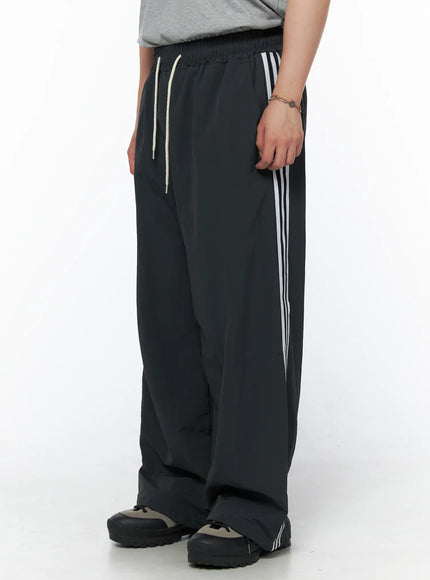Men's Striped Wide Track Pants IU523 dark gray side view on model showing white side stripe detail and cream drawstring waist