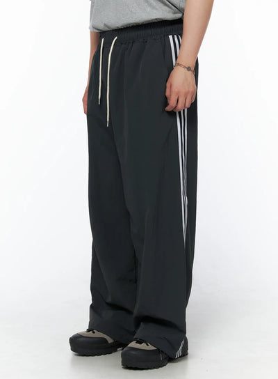 Men's Striped Wide Track Pants IU523 dark gray side view on model showing white side stripe detail and cream drawstring waist