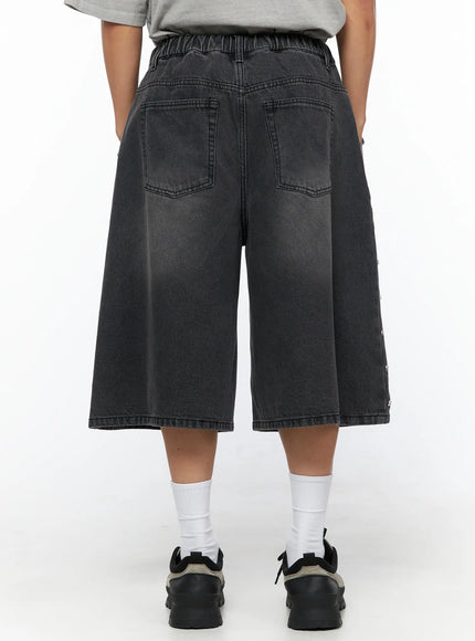 Men's Studded Jorts IL520 Black back view on model showing dual patch pockets, elastic waistband, wide-leg washed denim silhouette