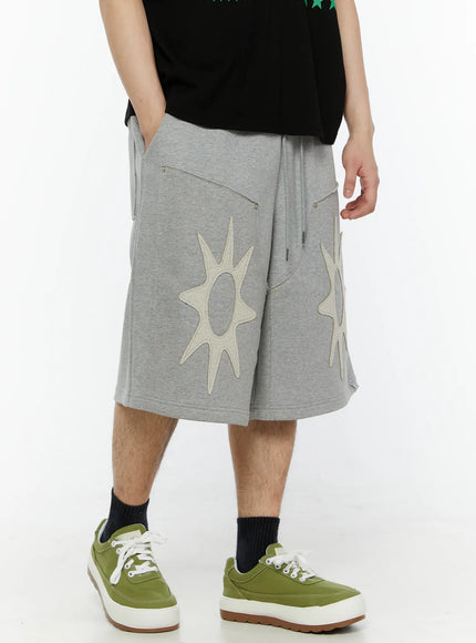 Men's Sun Embroidered Shorts (Gray) IL509 Gray angled front view on model showing side pocket zipper detail, cream sun appliqués on heathered cotton fabric