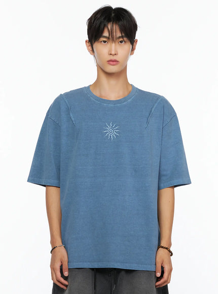 Men's Sun Embroidery T-Shirt IL520 Light blue upper-body front close-up on male model highlighting sun spiral embroidery on chest and raw seams