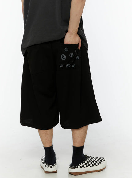 LEWKIN Men's Swirl Print Back Pocket Shorts (Black) IL509 Black M/L back shot on model hand in pocket showing swirl graphic print on back pocket wide-leg silhouette