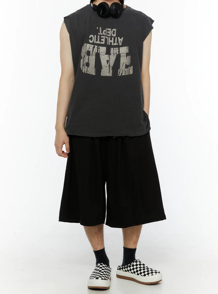 Men's Swirl Print Back Pocket Shorts (Black) IL509 Black full-body front shot on model standing straight styled with gray graphic sleeveless tee headphones and checkered slip-on shoes