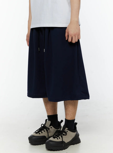 Men's Swirl Print Back Pocket Shorts (Dark Blue) IL509 Dark Blue front angled view on male model showing drawstring waist wide-leg drop and smooth jersey fabric texture