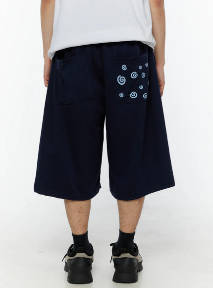 LEWKIN Men's Swirl Print Back Pocket Shorts (Dark Blue) IL509 Dark Blue back view on male model showing light blue swirl graphic on back pocket, wide-leg silhouette