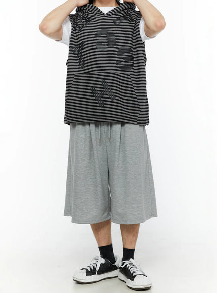 Men's Swirl Print Back Pocket Shorts (Gray) IL509 Gray dynamic front full-body view on model with hands in pockets styled with striped sleeveless hoodie and black sneakers