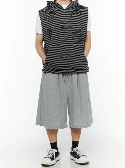 Men's Swirl Print Back Pocket Shorts (Gray) IL509 Gray full-body front view on model with hands raised adjusting hood showing relaxed wide-leg shorts with drawstring waist