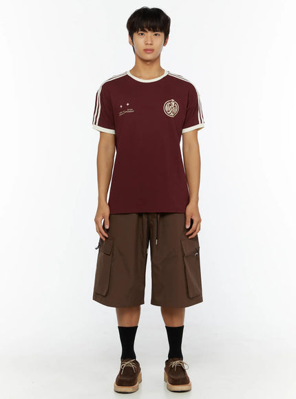 Men's Track Graphic T-Shirt IL507 Burgundy full-body front on model standing, styled with brown cargo shorts, black socks and suede lace-up shoes