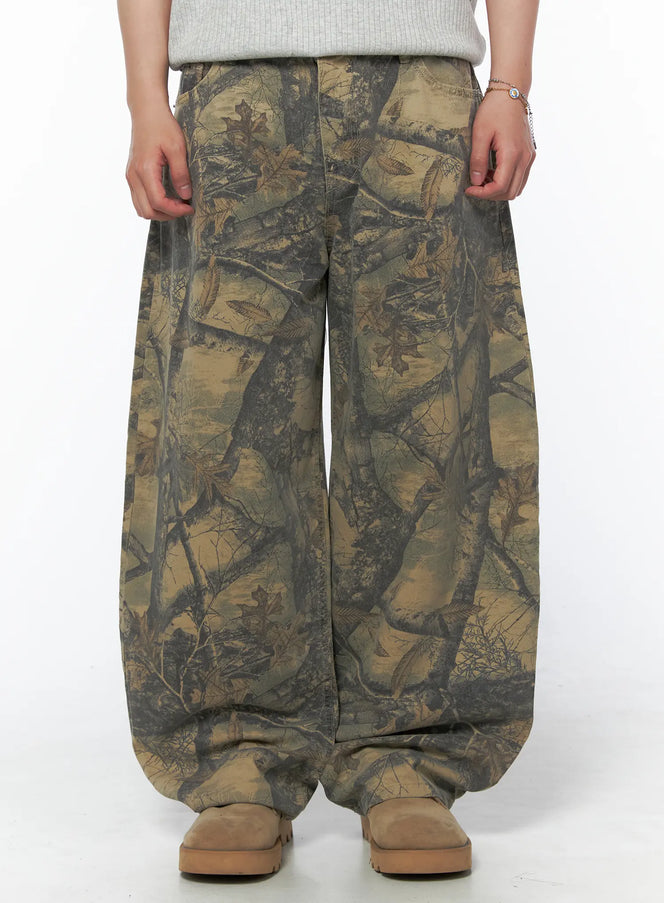 LEWKIN Men's Tree Graphic Wide Leg Pants IL502 Beige front close-up on model showing wide-leg silhouette and allover tree branch leaf camo print