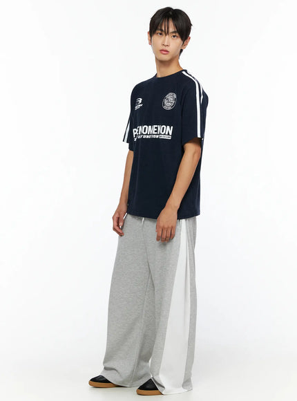Men's Two-Tone Sweatpants IL528 Gray three-quarter shot on male model styled with navy graphic tee showing white side panel detail and relaxed wide-leg silhouette