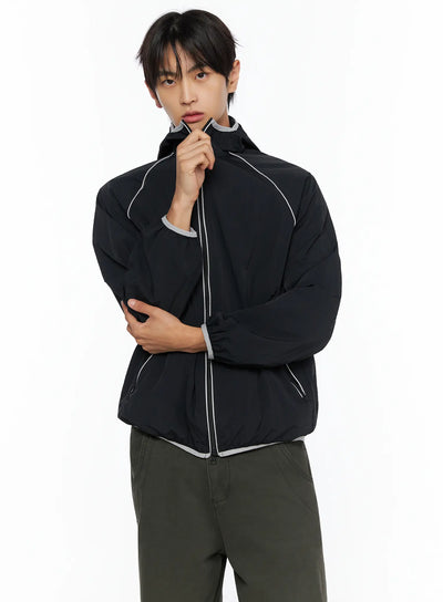LEWKIN Men's Two-Tone Windbreaker IL528 Black front close-up on male model, one hand gripping zipper, grey contrast piping detail, nylon shell