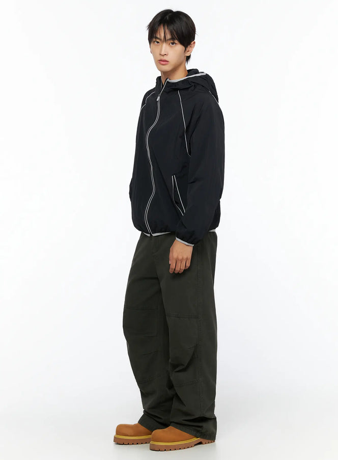 Men's Two-Tone Windbreaker IL528 Black side view on male model, full-length outfit with dark olive cargo pants and tan boots, grey contrast trim