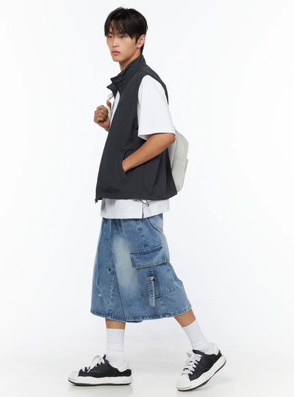 Men's Two-Way Anorak Vest IL515 Dark gray side shot on male model walking pose with backpack, showing vest silhouette and layering over white tee