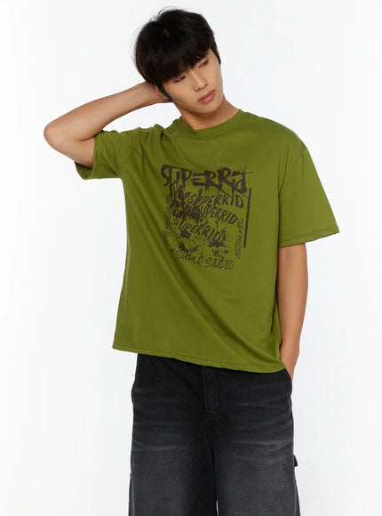 Men's Typography Graphic T-Shirt IL513 Green three-quarter front shot on male model hand raised behind head showcasing bold graffiti chest print