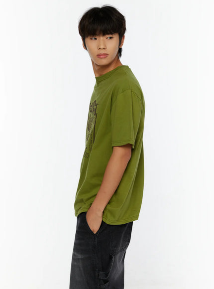 Men's Typography Graphic T-Shirt IL513 Green side shot on male model hand in pocket showing graffiti-style dark print on olive cotton tee