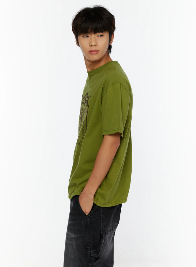 Men's Typography Graphic T-Shirt IL513 Green side shot on male model hand in pocket showing graffiti-style dark print on olive cotton tee