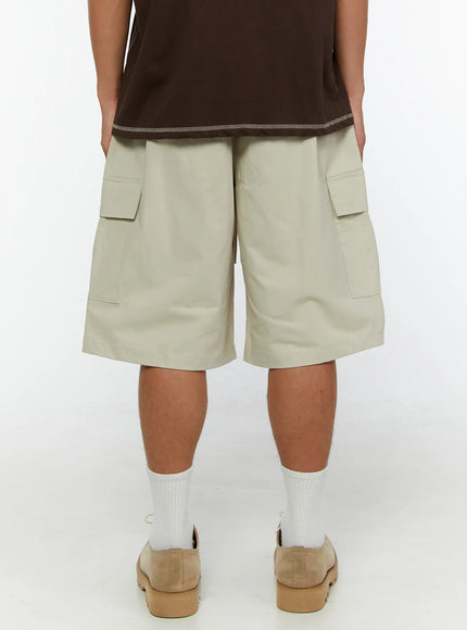 Men's Utility Cargo Shorts IL513 Beige back view on model showing rear cargo pockets and wide boxy silhouette paired with brown tee