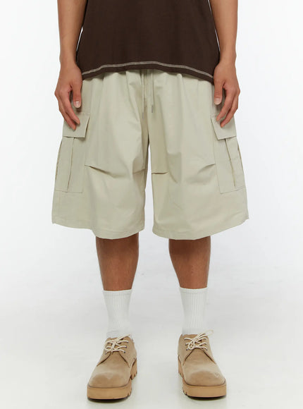 Men's Utility Cargo Shorts IL513 Beige front close-up on model showing dual flap cargo pockets and drawstring waistband detail