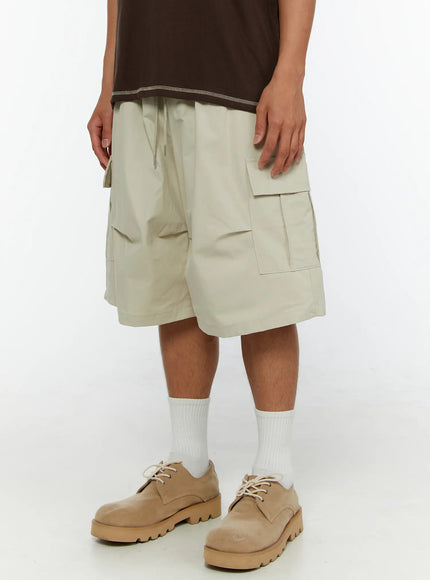 Men's Utility Cargo Shorts IL513 Beige three-quarter front shot on model showing wide-leg silhouette, cargo pockets and elastic waistband