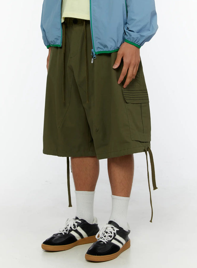 Men's Utility Pocket Cargo Shorts IL515 olive green angled side close-up on model showing ribbed cargo pocket detail and hem drawstring cords