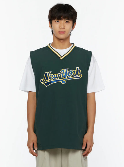 Men's Varsity Style Graphic Tank IL509 green close-up front shot on male model showing New York varsity script graphic with yellow outline and striped V-neckline trim detail
