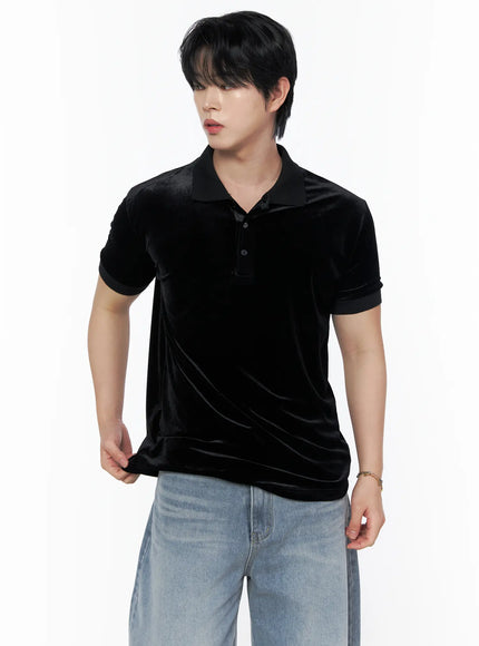 Men's Velvet Polo Shirt IL502 Black cropped front shot on model holding hem showing button placket velvet sheen and contrast black cuffs