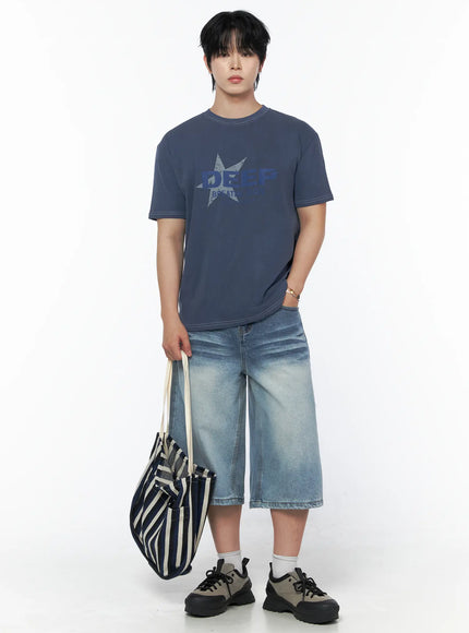 Men's Vintage Wash Jorts IU523 Light blue full-body front shot on male model in navy graphic tee holding striped tote bag, wide-leg denim jorts styled casually
