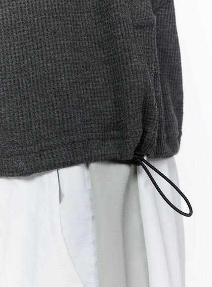 Men's Waffle Knit Zip-Up Sleeveless Hoodie IL515 dark close-up detail shot of hem drawcord toggle and waffle knit fabric texture at lower body