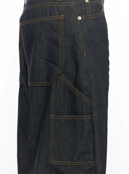 Men's Washed Wide Leg Jeans IL510 Black close-up detail of front left carpenter pocket with angular stitching panels and orange contrast topstitching on dark denim
