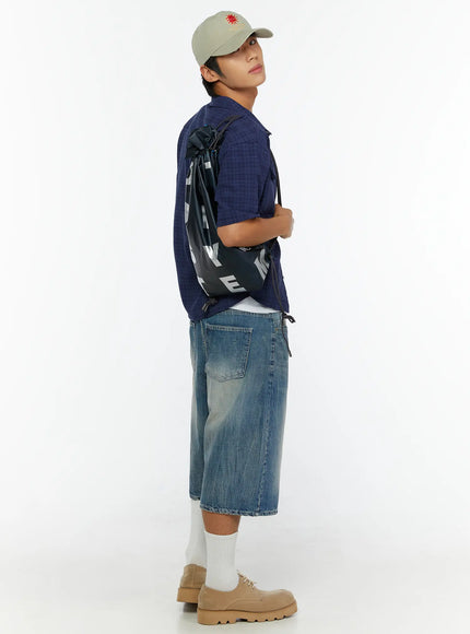 Men's Washed Wide Leg Jorts IL513 Blue side full-body shot on model carrying drawstring bag over shoulder, showing wide leg volume and back pocket detail with cap