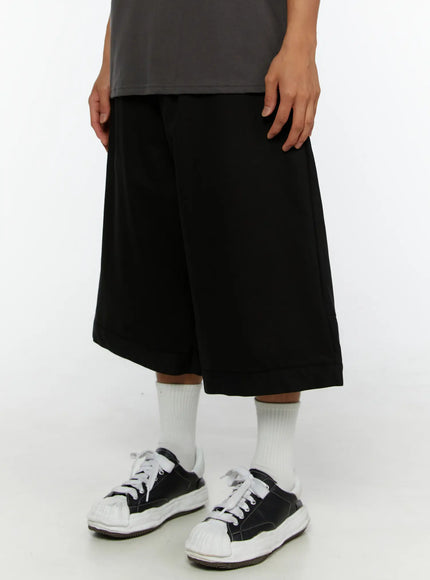 Men's WIde Cargo Bermuda Shorts IL513 Black front close-up side angle on model showing wide-leg hem and pocket detail with sneakers