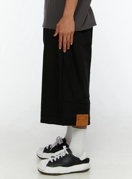 Men's WIde Cargo Bermuda Shorts IL513 Black side view on model showing side pocket, cuffed hem, and Original Jeans leather patch detail