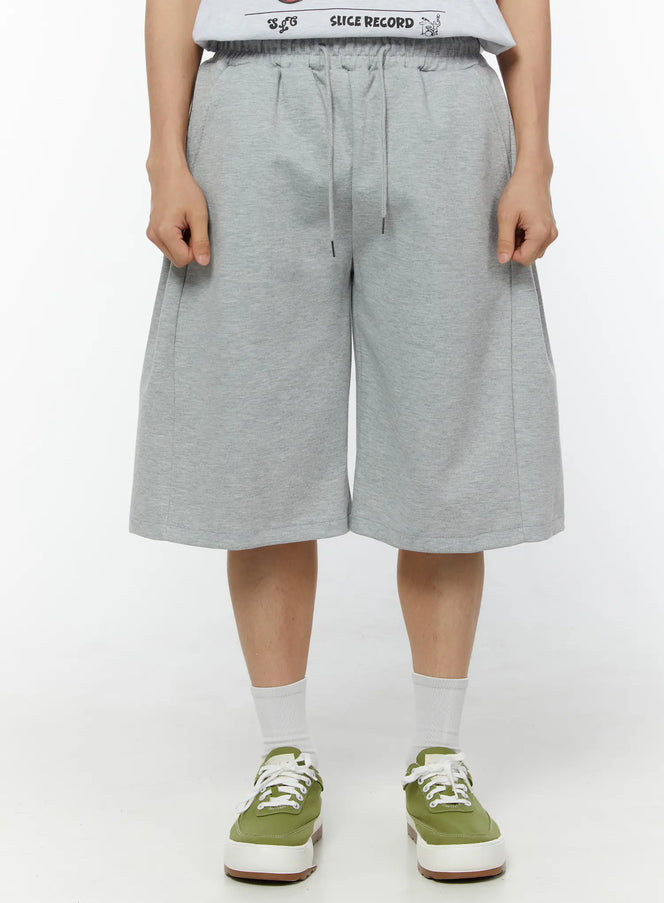Men's Wide Leg Bermuda Sweat Shorts (Gray) IU529 Gray front view on model standing straight showing drawstring elastic waist wide-leg cut and center seam in heathered cotton fleece
