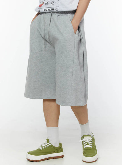 LEWKIN Men's Wide Leg Bermuda Sweat Shorts (Gray) IU529 Gray M/L angled side view on model hands in pockets showing wide-leg silhouette and drawstring waist in heathered cotton fleece