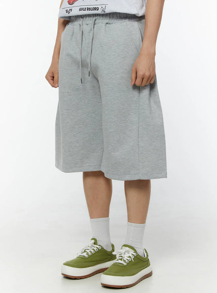 Men's Wide Leg Bermuda Sweat Shorts (Gray) IU529 Gray side view on model showing full length hem side pocket and clean seam line of wide-leg silhouette in heathered cotton fleece